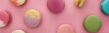 pattern of multicolored delicious French macaroons on pink background, panoramic shot clipart