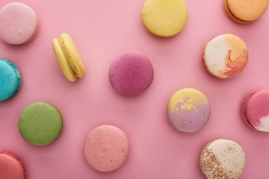 pattern of multicolored tasty French macaroons scattered on pink background clipart