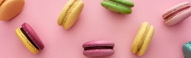 pattern of multicolored tasty French macaroons scattered on pink background, panoramic shot clipart