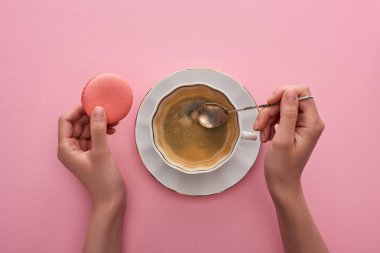 fincan kahve ve pembe arka plan üzerinde lezzetli Fransız makarna yanında kaşık tutan kadın kısmi görünümü