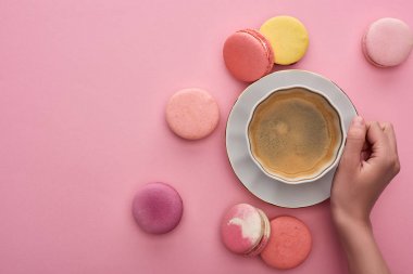 pembe arka plan üzerinde lezzetli Fransız macaroons ile kahve içen kadın kırpılmış görünümü