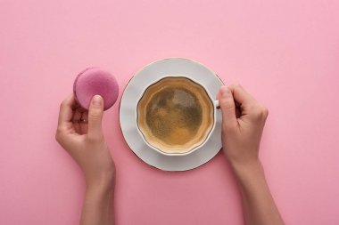 pembe arka plan üzerinde lezzetli Fransız macaroon ile kahve içen kadın kırpılmış görünümü