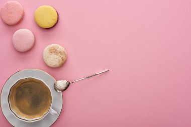 kopya alanı ile pembe arka plan üzerinde kaşık ile kahve yakınında lezzetli Fransız macaroons üst görünümü