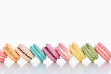 row of delicious colorful French macaroons of different flavors on white background with copy space clipart