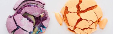 top view of delicious orange and purple smashed French macaroons isolated on white, panoramic shot clipart