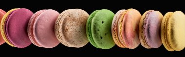 row of delicious colorful French macaroons of different flavors isolated on black, panoramic shot clipart