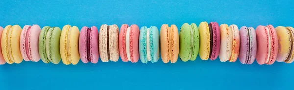 Plano Panorámico Macarrones Franceses Deliciosos Multicolores Fila Sobre Fondo Azul — Foto de Stock