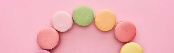 frame of delicious French macaroons on pink background, panoramic shot