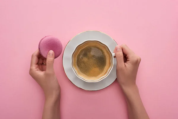 ピンクの背景においしいフランスのマカロンでコーヒーを飲む女性のトリミングビュー — ストック写真