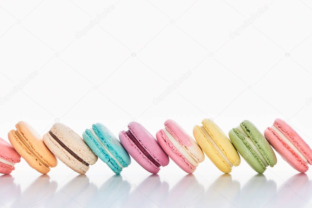 row of delicious colorful French macaroons of different flavors on white background with copy space
