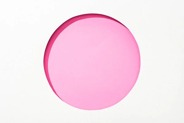 在粉红色彩色背景的白纸上切出圆孔 — 图库照片