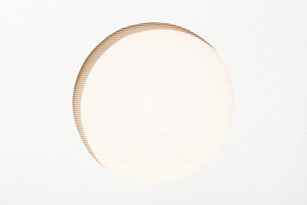 cut out round hole in white paper on beige striped colorful background