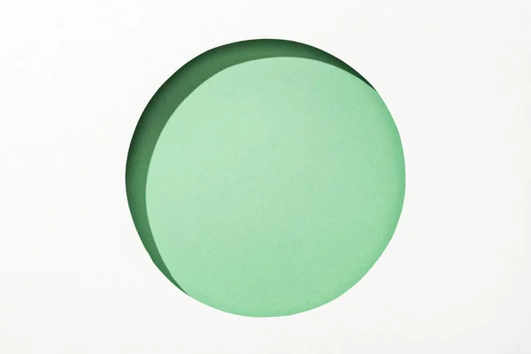 在绿色背景的白纸上切出圆孔 — 图库照片