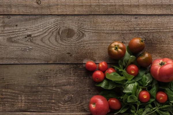 top view of tomatoes with spinach on wooden table 