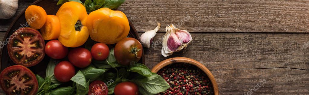 Panoramic shot of spinach and sliced tomatoes on plate near garlic, chilli pepper and bowl with pepper on wooden table — Stock Image Panoramic Shot Spinach Sliced Tomatoes Plate Garlic Chilli Pepper Bowl Royalty Free Stock Images