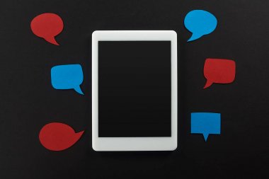 top view of digital tablet with blank screen on black background with empty red and blue speech bubbles, cyberbullying concept clipart