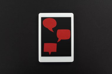 siyah arka plan üzerinde boş kırmızı konuşma kabarcıkları ile dijital tablet üst görünümü, siber zorbalık kavramı
