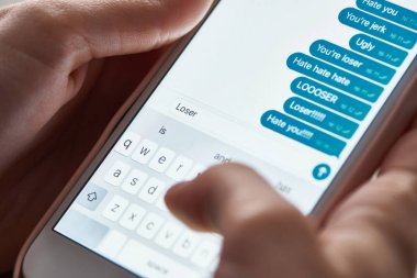akıllı telefon kullanırken saldırgan mesajlar gönderen tacizcinin kısmi görünümü, açıklayıcı editoryal