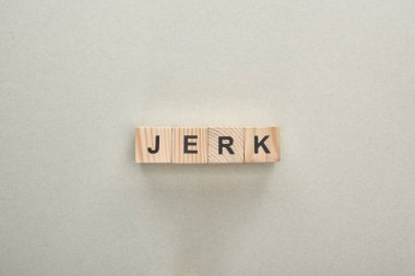 top view of wooden blocks with jerk lettering on grey background, bullying concept clipart