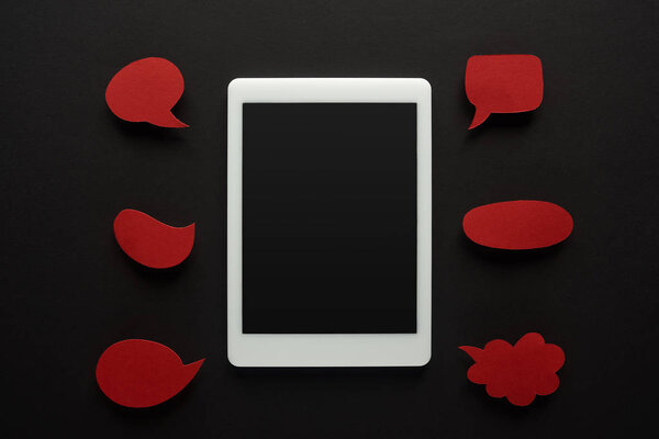 top view of digital tablet with blank screen on black background with empty red speech bubbles, cyberbullying concept