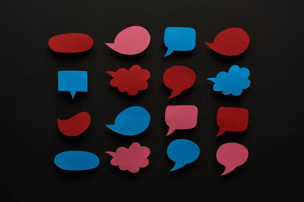 top view of empty speech bubbles on black background, cyberbullying concept