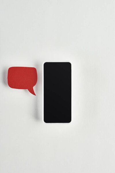 top view of smartphone on white background near red empty speech bubble, cyberbullying concept