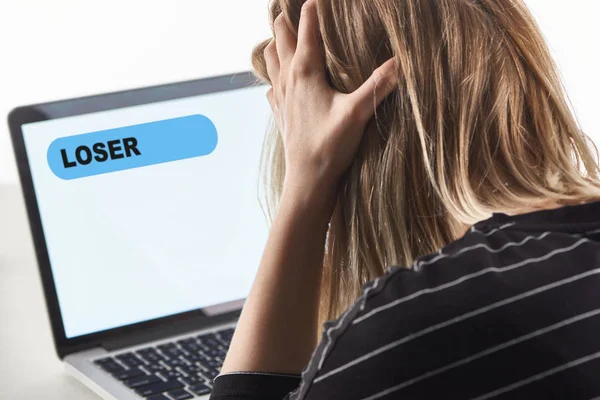 得罪金发女孩作为网络欺凌的受害者坐在笔记本电脑附近与失败者的消息在屏幕上 — 图库照片