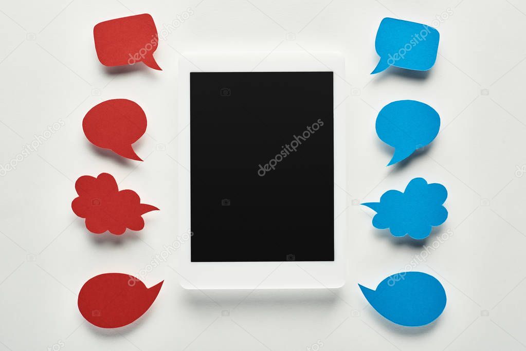 top view of digital tablet with blank screen on white background near empty red and blue speech bubbles, cyberbullying concept