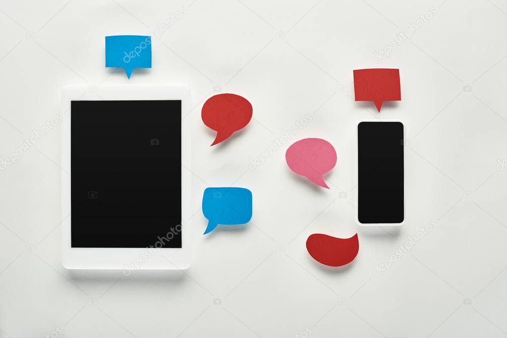 top view of digital tablet ad smartphone with blank screen on white background near empty speech bubbles, cyberbullying concept