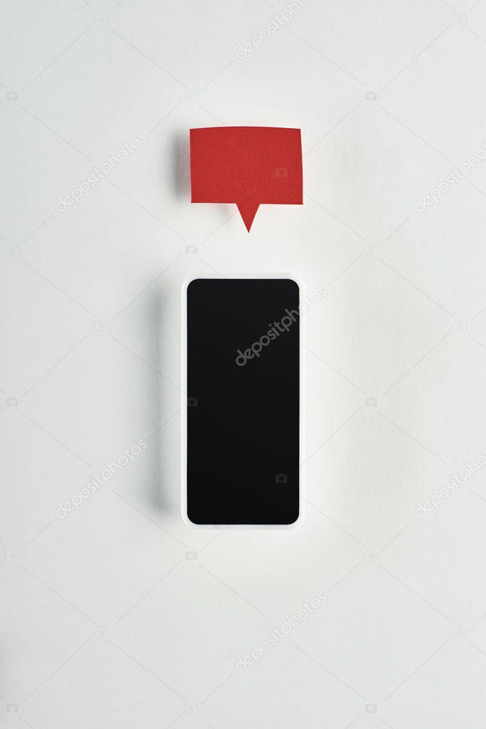 top view of smartphone with blank screen on white background with red empty speech bubble above, cyberbullying concept