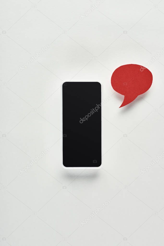 top view of smartphone with blank screen on white background near red empty speech bubble, cyberbullying concept