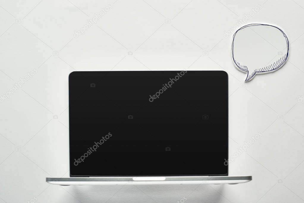 laptop with blank screen on white background near empty speech bubble, cyberbullying concept