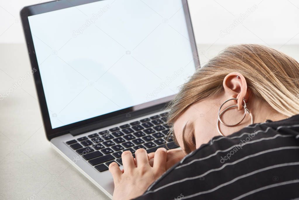 blonde girl sleeping near laptop with blank screen, cyberbullying concept