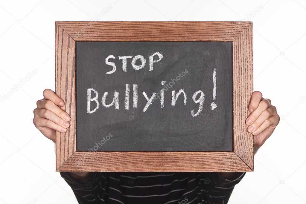 girl holding chalkboard in wooden frame with stop bullying lettering isolated on white