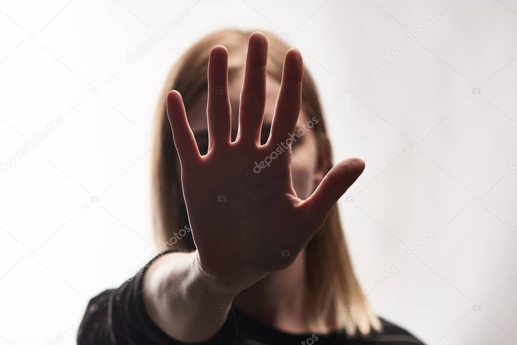 selective focus of victim of bullying showing stop sign isolated on white