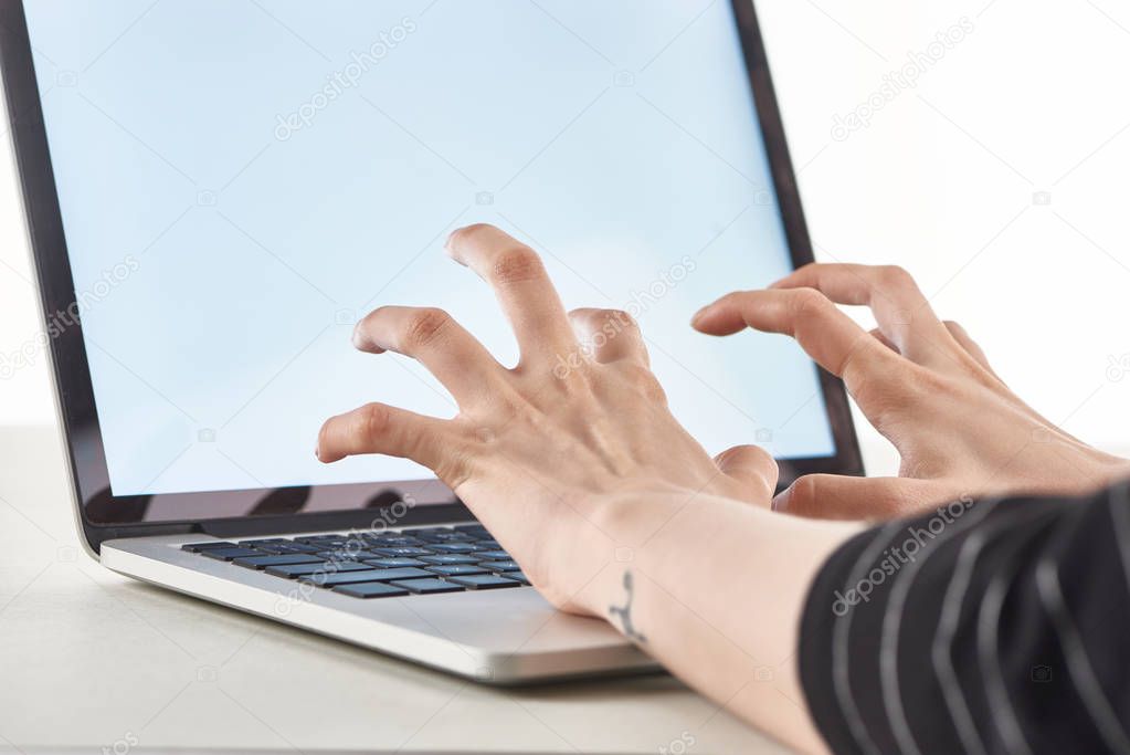 cropped view of angry girl typing on laptop keyboard isolated on white, cyberbullying concept
