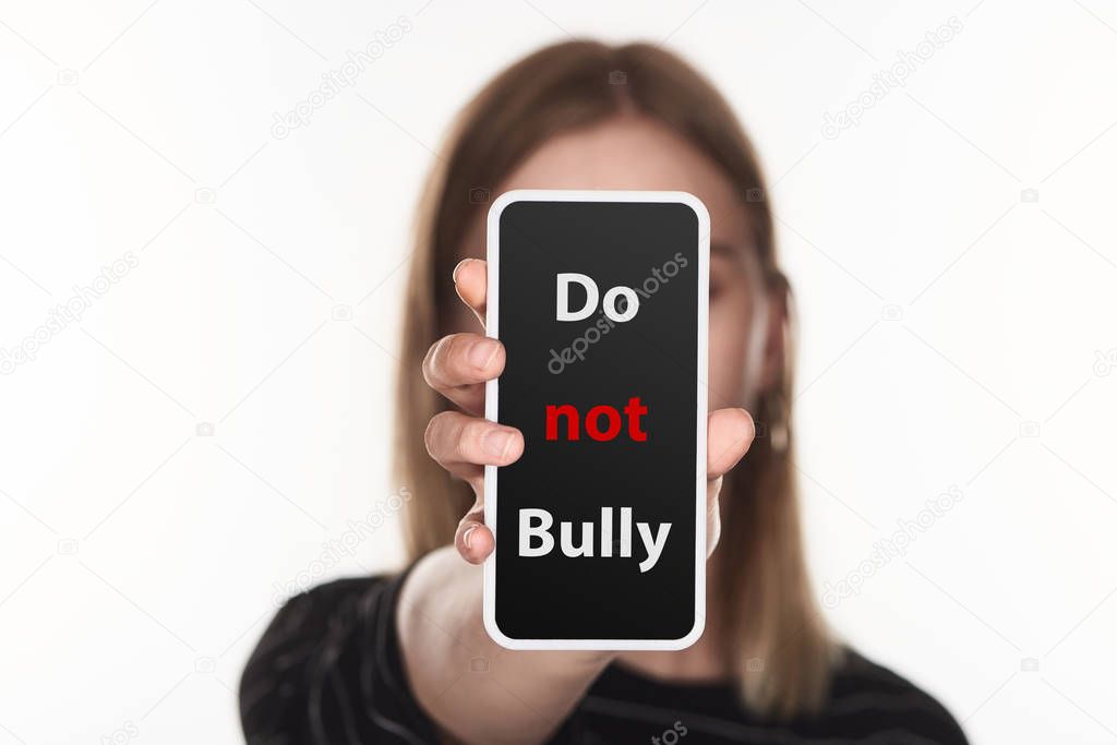 selective focus of victim of cyberbullying showing smartphone with do not bully lettering on screen isolated on white