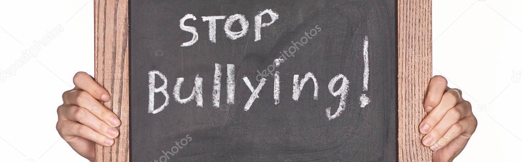 panoramic shot of girl holding chalkboard in wooden frame with stop bullying lettering isolated on white