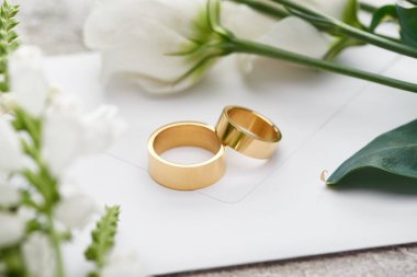 beyaz eustoma çiçekleri yakınında beyaz zarf üzerinde alyans seçici odak