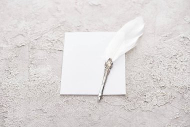 quill pen on white empty card on grey textured surface clipart
