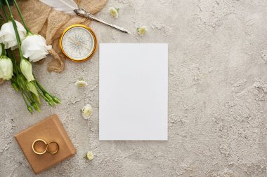 boş kart, pusula, dağınık çiçekler, hediye kutusu ve gri dokulu yüzeyüzerinde beyaz eustoma çiçekler üzerinde altın yüzük yakın bej çuval bezi üzerinde quill kalem üst görünümü