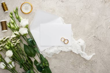 boş kart, beyaz cheesecloth, altın pusula ve gri dokulu yüzeyüzerinde bobinler üzerinde alyans yakınında eustoma çiçeklerüst görünümü 