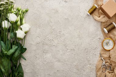 dokulu yüzeyde bej çuval bezi üzerinde hediye kutusu, pusula, makas ve bobinler yakın eustoma çiçek üst görünümü 