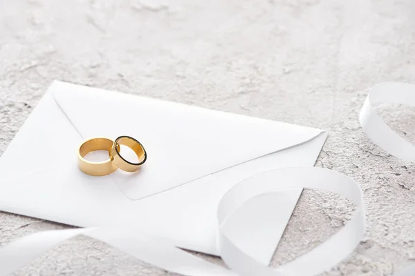 Anéis Dourados Envelope Perto Fita Branca Superfície Texturizada Cinzenta — Fotografia de Stock