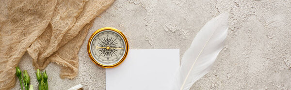 panoramic shot of quill pen on piece of paper near beige sackcloth and golden compass on grey textured surface