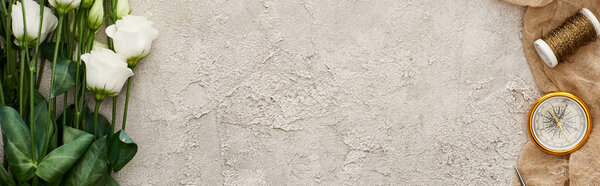 панорамный снимок белых роз рядом с компасом и рулон проволоки на мешковине на текстурированной поверхности с копировальным пространством
