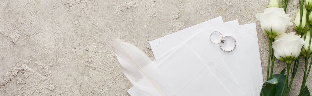 panoramic shot of silver rings on invitation cards near white eustoma flowers on textured surface 