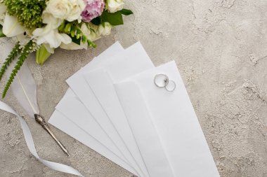 dokulu yüzeyde quill kalem, beyaz kurdele ve buket yakın zarflar üzerinde alyans üst görünümü 