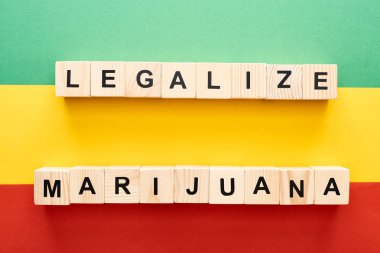 top view of wooden blocks with legalize marijuana lettering on Rastafarian flag clipart