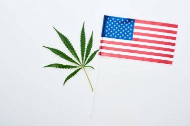 top view of green cannabis leaf near american flag on white background clipart